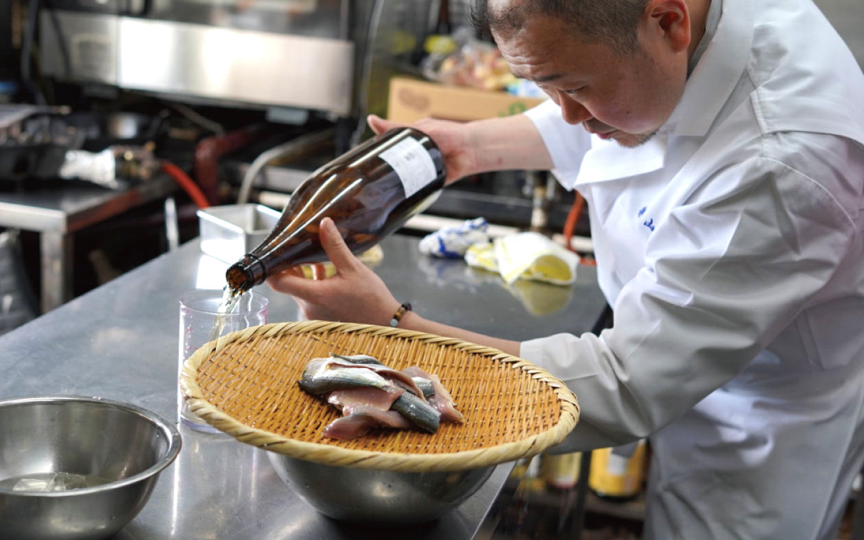 酒をつぎ調理をする店主